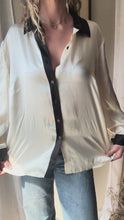 Load and play video in Gallery viewer, Vintage Deadstock Silk Ivory White Satin Oversized Button Up Blouse Black Collar and Sleeve Cuffs
